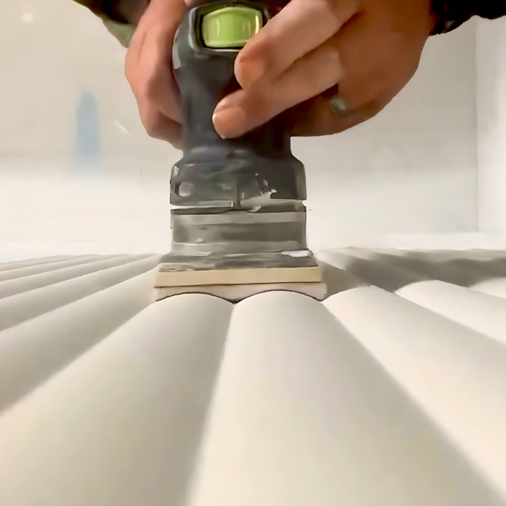 
                  
                    Close-up of hands using a TradeGear TRADEgear XP Foam Abrasive Pad 80mm x 133mm to smooth the ridged surface of wood.
                  
                